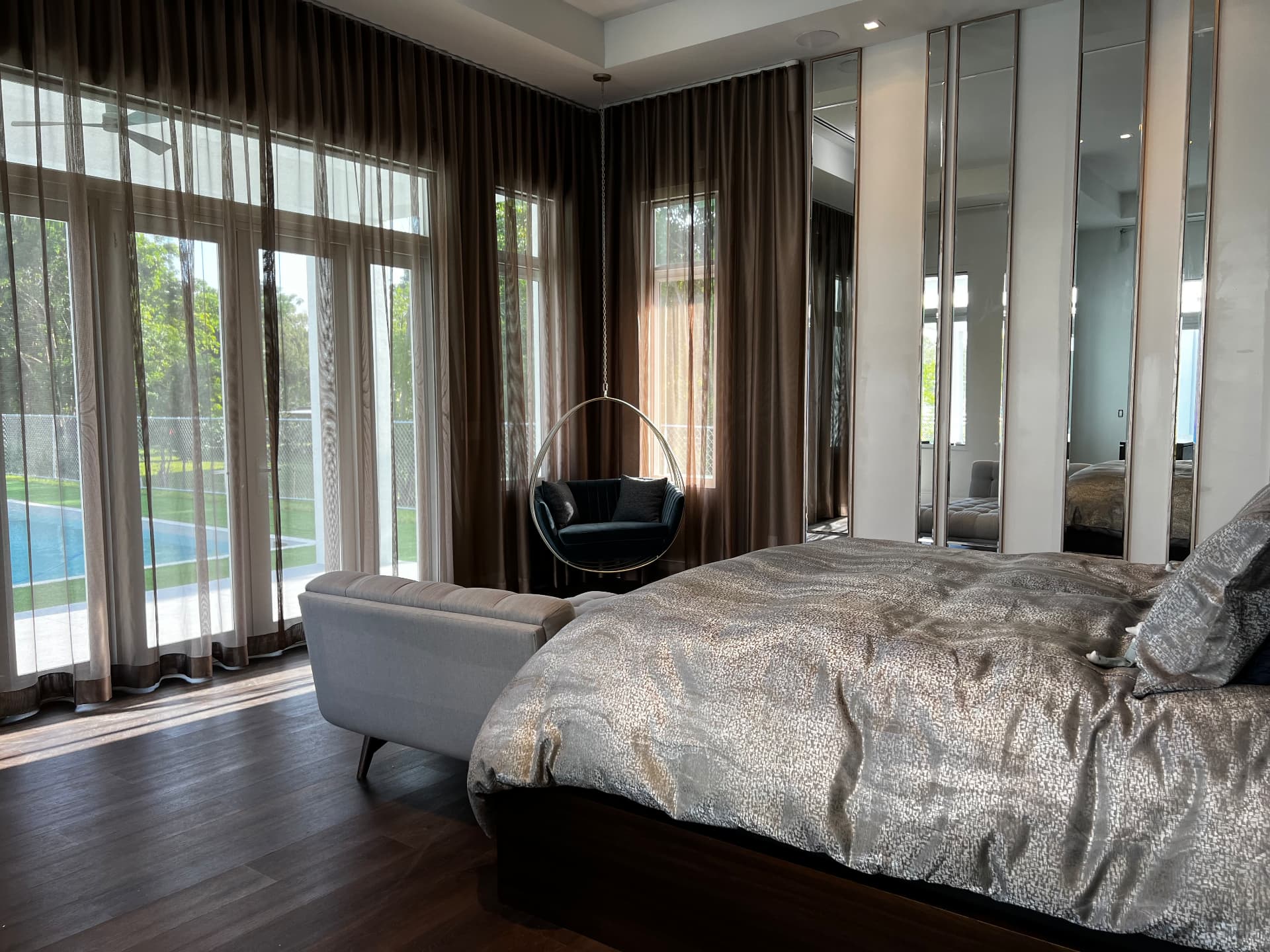 Waterfront estate primary bedroom with layered sheer and opaque drapery