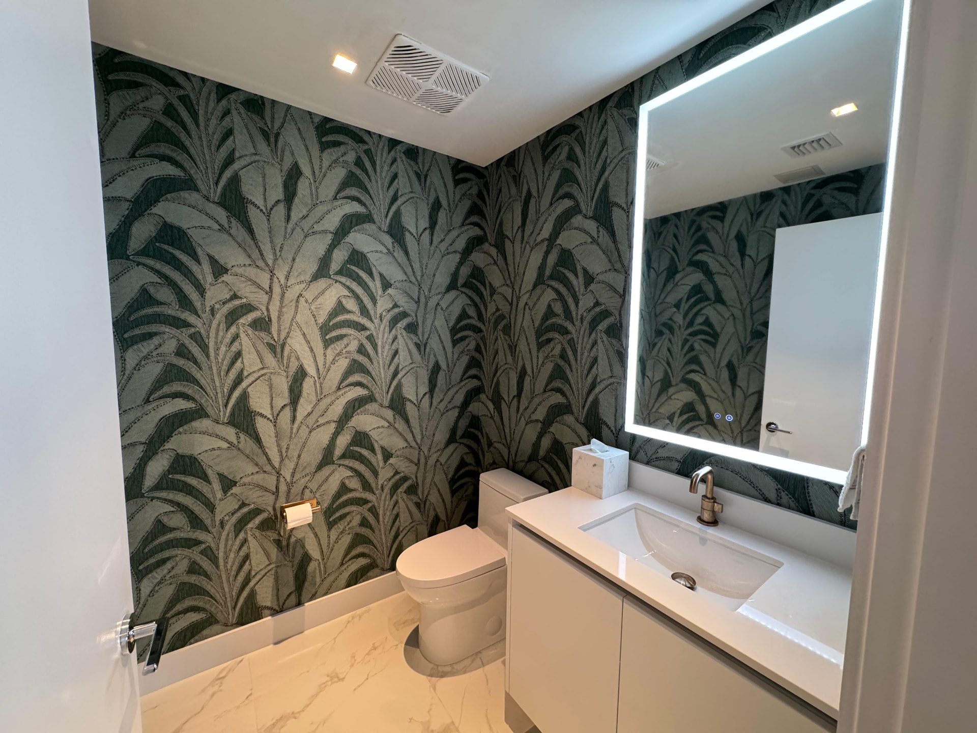Aria Reserve powder room with deep green palm-leaf wallcovering