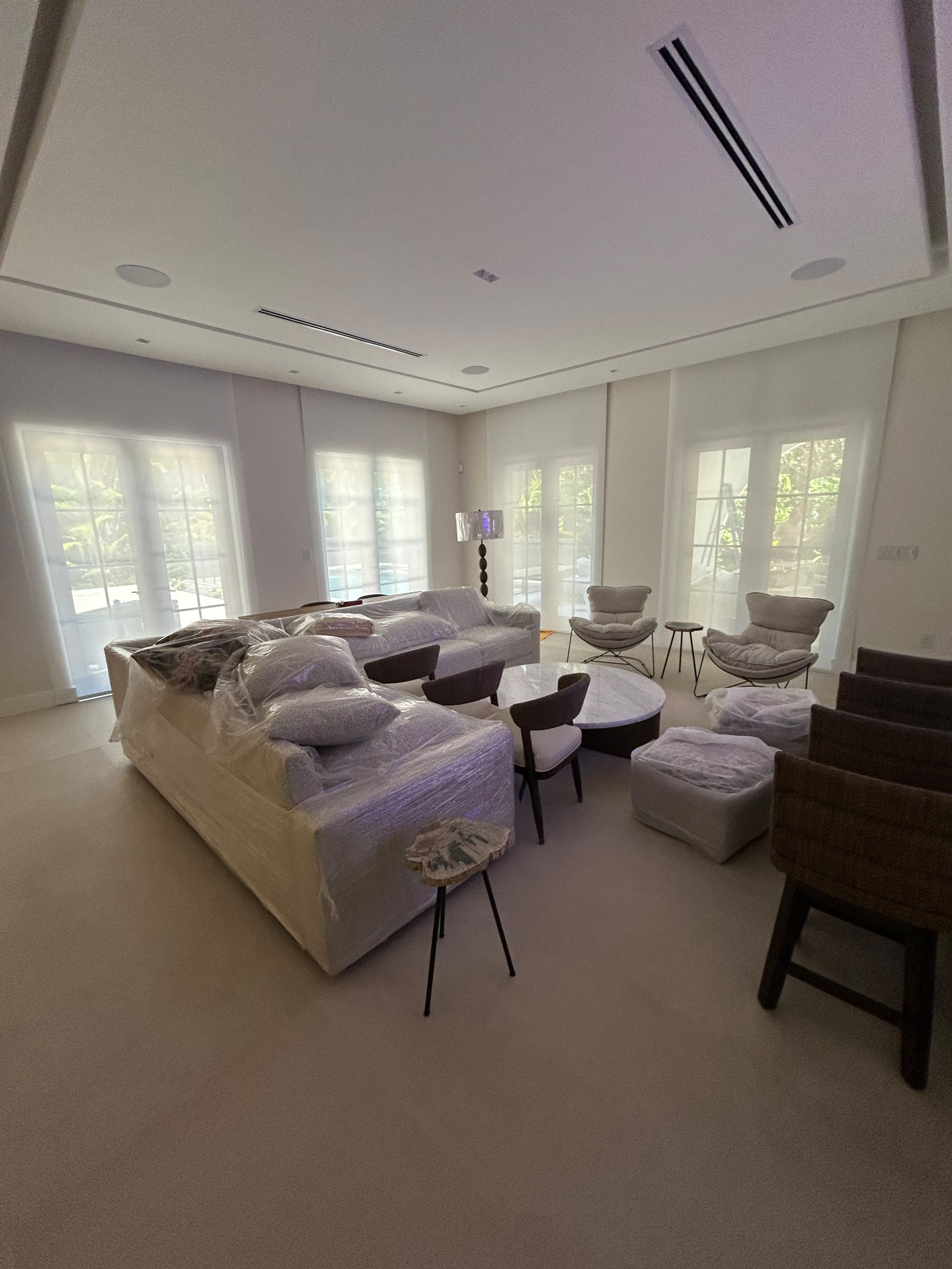 Doral Isles living room during installation of multiple white roller shades