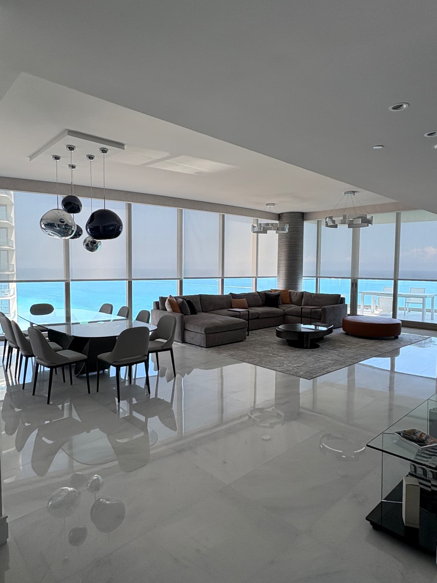 Aria Reserve open living and dining area with solar shades on the ocean-facing glass